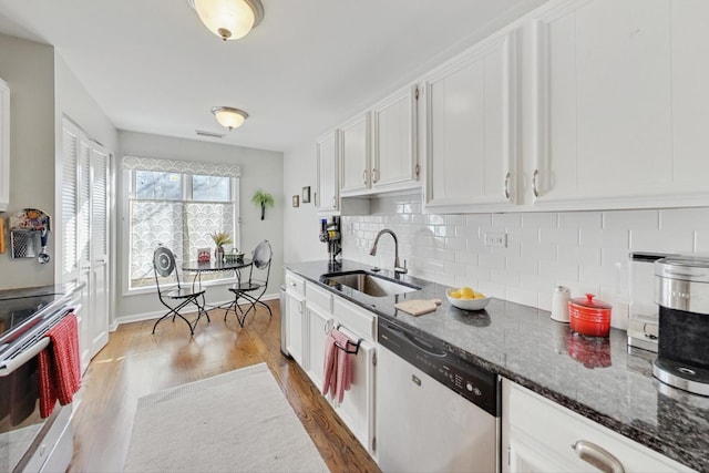 kitchen with hardwood / wood-style floors, appliances with stainless steel finishes, dark stone countertops, white cabinets, and sink