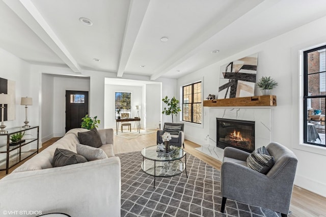 living room featuring beam ceiling, a fireplace, and light hardwood / wood-style flooring