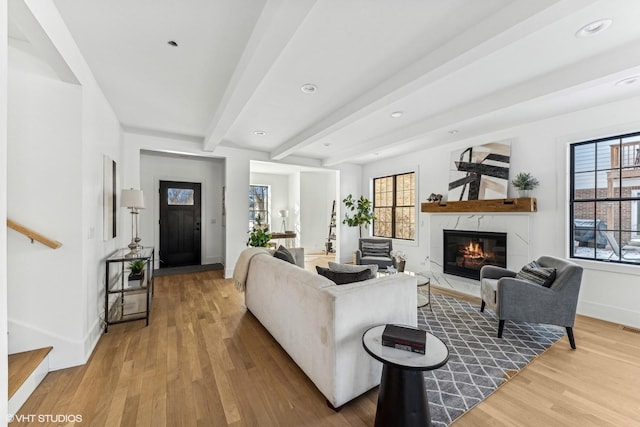 living room featuring hardwood / wood-style floors, plenty of natural light, beam ceiling, and a large fireplace