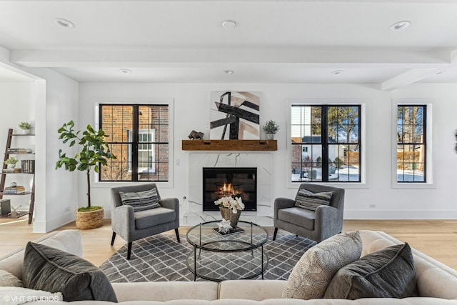 living room with a fireplace, beam ceiling, light hardwood / wood-style flooring, and a healthy amount of sunlight