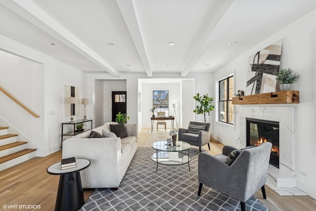 living room with hardwood / wood-style floors, beam ceiling, and a premium fireplace