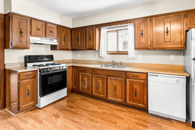 kitchen with sink, dishwasher, gas range oven, a textured ceiling, and light wood-type flooring