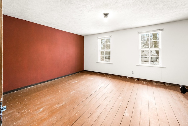 empty room with hardwood / wood-style flooring, a healthy amount of sunlight, and a textured ceiling