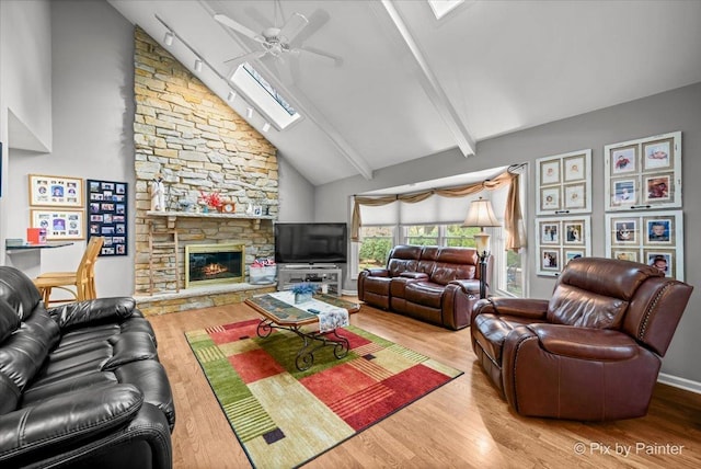 living room featuring a fireplace, wood-type flooring, a skylight, and ceiling fan