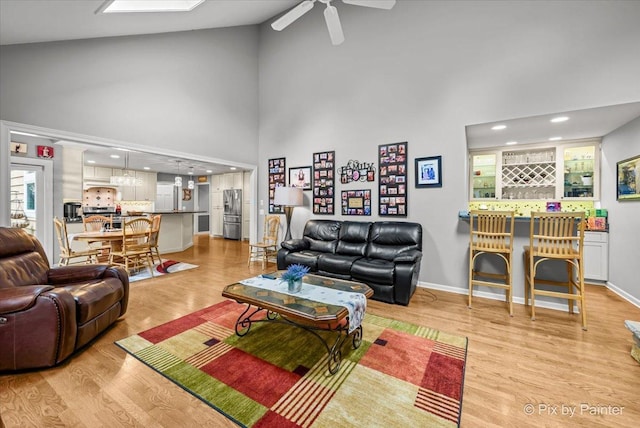 living room featuring ceiling fan, high vaulted ceiling, and light hardwood / wood-style floors