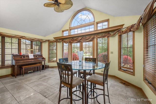 dining area with ceiling fan, light tile patterned flooring, and vaulted ceiling