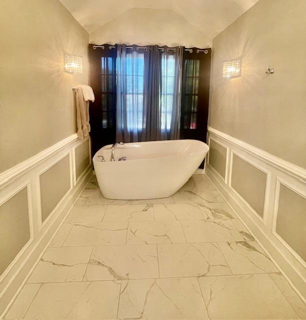 bathroom with lofted ceiling and a tub to relax in