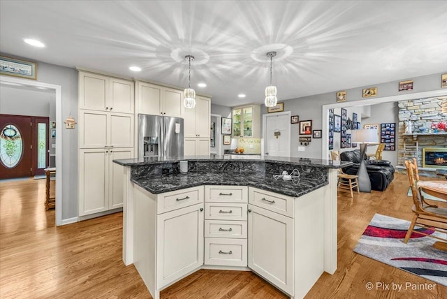 kitchen with dark stone counters, stainless steel fridge, a center island, and pendant lighting