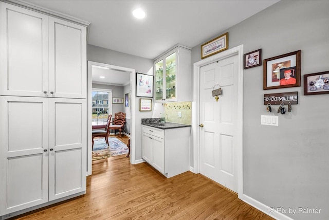 kitchen featuring decorative backsplash, light hardwood / wood-style flooring, and white cabinets