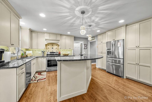 kitchen featuring a center island, sink, light wood-type flooring, decorative light fixtures, and stainless steel appliances