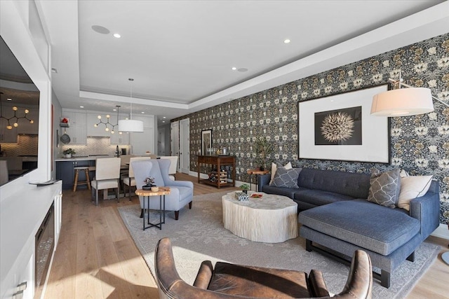 living room with a tray ceiling and light hardwood / wood-style flooring