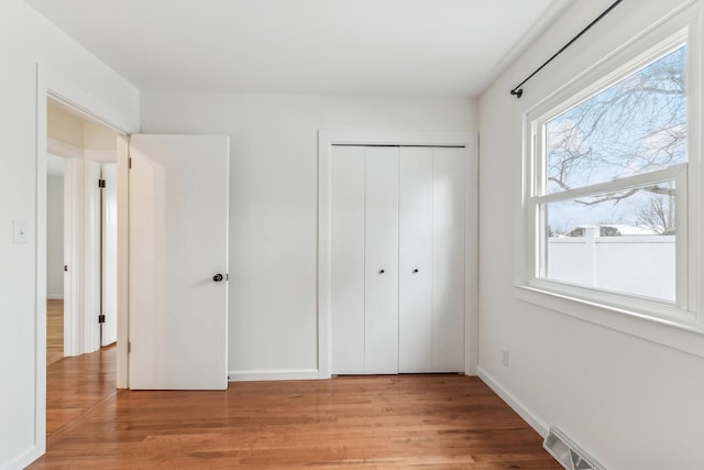 unfurnished bedroom featuring multiple windows and light hardwood / wood-style flooring