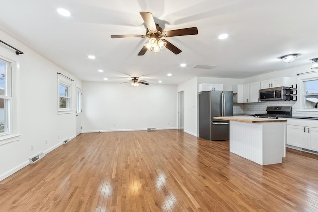 kitchen with stainless steel appliances, tasteful backsplash, light hardwood / wood-style flooring, wooden counters, and white cabinets