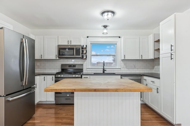 kitchen featuring wood counters, white cabinets, sink, a kitchen island, and stainless steel appliances