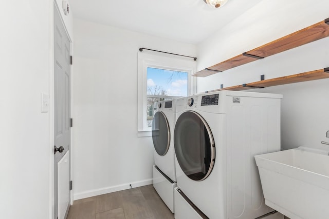 laundry room with wood-type flooring, independent washer and dryer, and sink