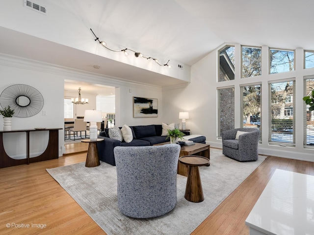 living room featuring hardwood / wood-style flooring, ornamental molding, a healthy amount of sunlight, and a notable chandelier