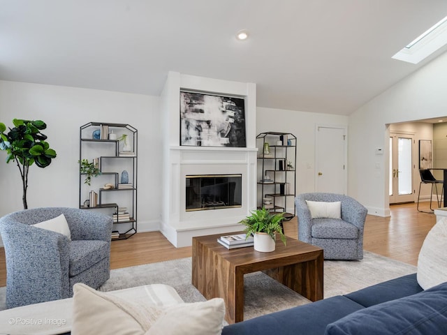 living room with light hardwood / wood-style flooring and vaulted ceiling with skylight