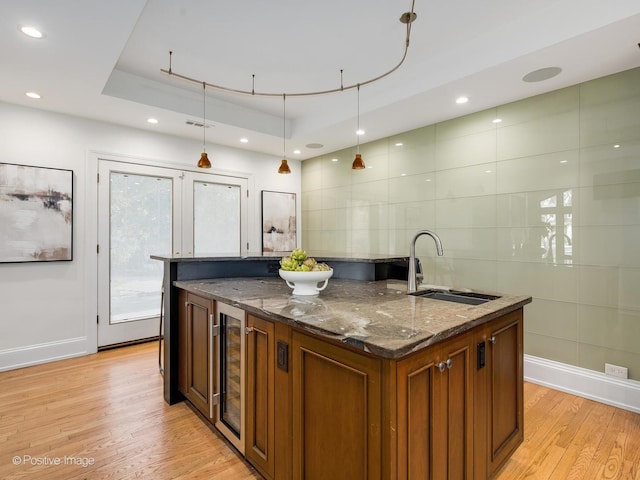 kitchen featuring pendant lighting, sink, dark stone counters, and an island with sink