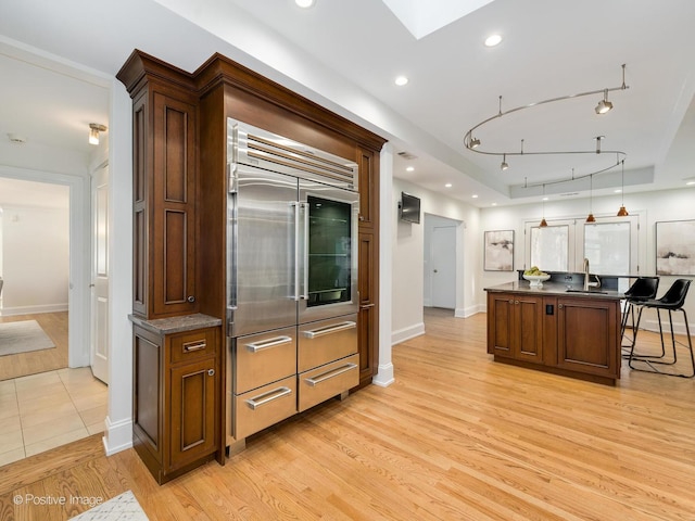 kitchen featuring sink, a kitchen bar, a skylight, light hardwood / wood-style floors, and a kitchen island