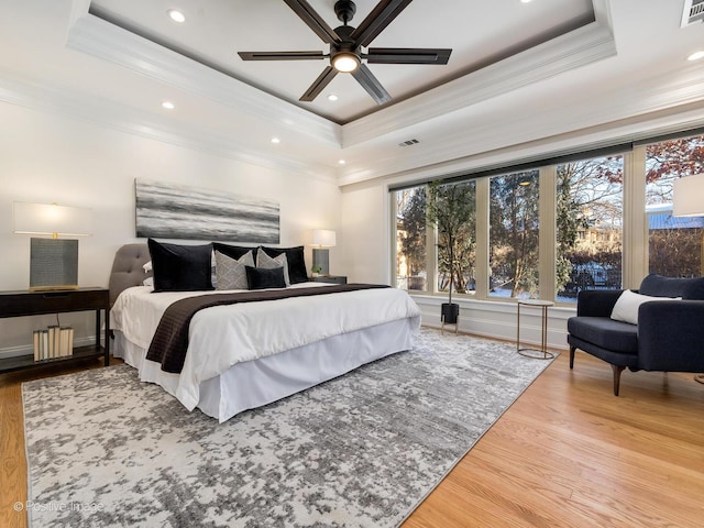 bedroom with ornamental molding, a raised ceiling, and hardwood / wood-style floors