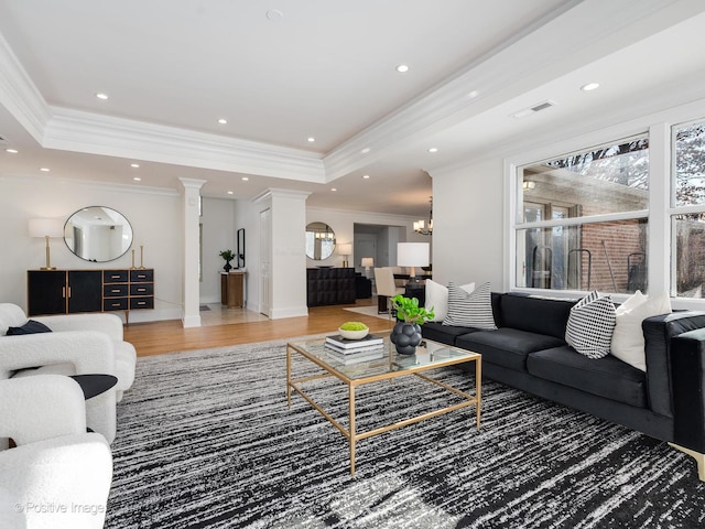 living room with a chandelier, wood-type flooring, a raised ceiling, and decorative columns