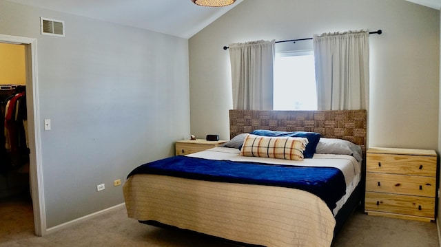 carpeted bedroom with a walk in closet, lofted ceiling, and a closet