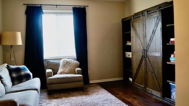 living area with a barn door and dark hardwood / wood-style floors