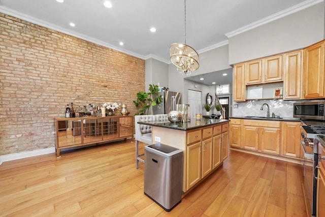 kitchen with hanging light fixtures, brick wall, a kitchen island, sink, and premium appliances