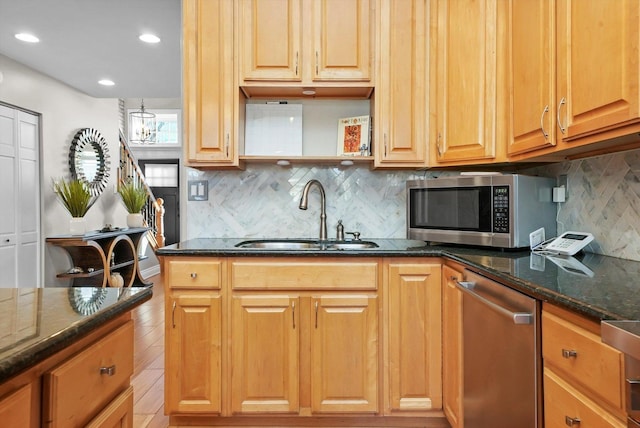 kitchen featuring sink, stainless steel appliances, dark stone countertops, and backsplash