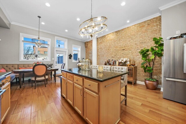 kitchen featuring brick wall, stainless steel fridge, hanging light fixtures, and a center island