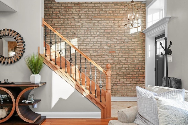 stairway featuring a notable chandelier and brick wall