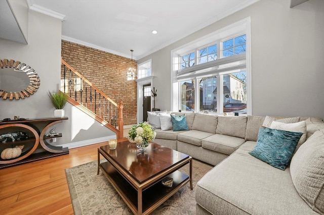 living room featuring brick wall, wood-type flooring, ornamental molding, and a notable chandelier