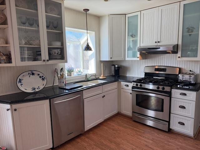 kitchen with stainless steel appliances, sink, decorative light fixtures, white cabinets, and hardwood / wood-style floors