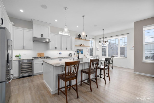 kitchen featuring appliances with stainless steel finishes, beverage cooler, white cabinetry, and a breakfast bar