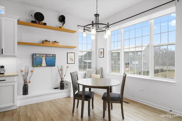 dining space featuring light hardwood / wood-style floors and a notable chandelier