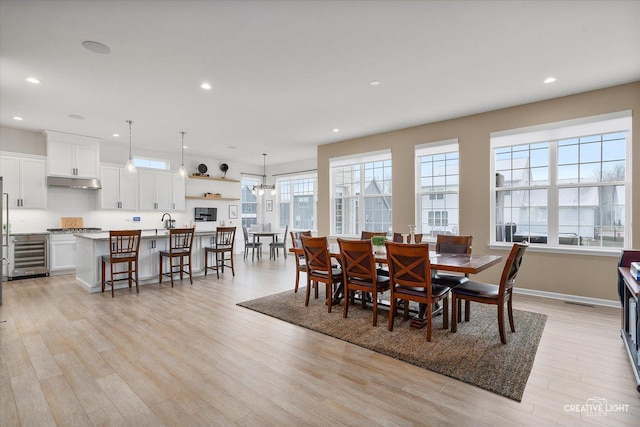 dining room with a healthy amount of sunlight, sink, beverage cooler, and light hardwood / wood-style floors