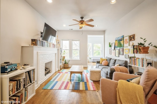 living room with ceiling fan, light hardwood / wood-style flooring, and a fireplace