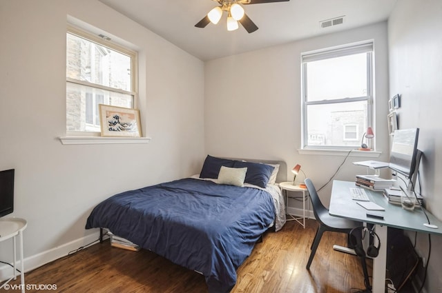 bedroom featuring hardwood / wood-style flooring, ceiling fan, and multiple windows