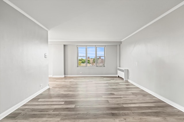 unfurnished room featuring radiator, light wood-type flooring, and crown molding