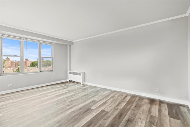 spare room with radiator, light wood-type flooring, and crown molding