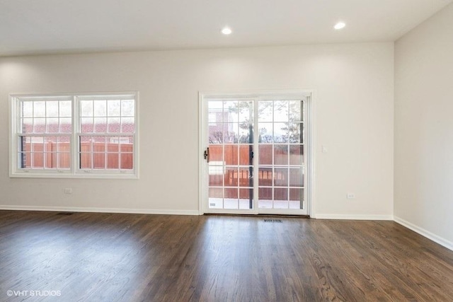 spare room with dark hardwood / wood-style floors and plenty of natural light