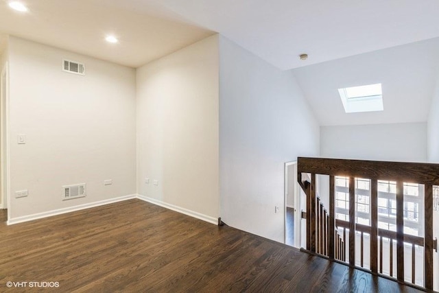 spare room with vaulted ceiling with skylight and dark wood-type flooring