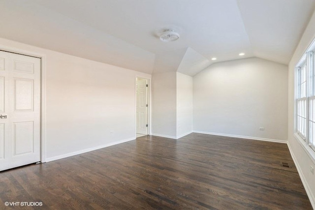 empty room featuring dark hardwood / wood-style flooring, a wealth of natural light, and vaulted ceiling