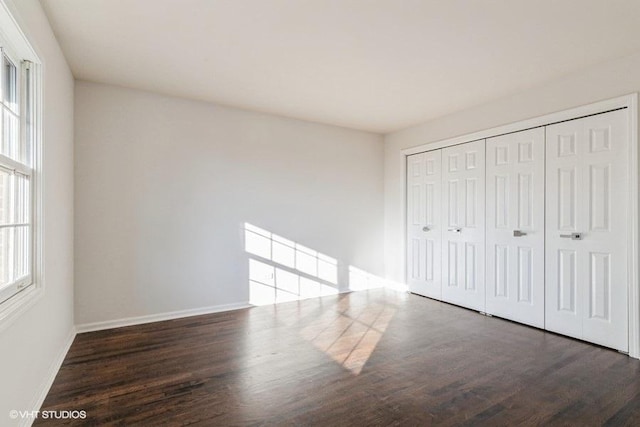 unfurnished bedroom with dark hardwood / wood-style flooring and a closet