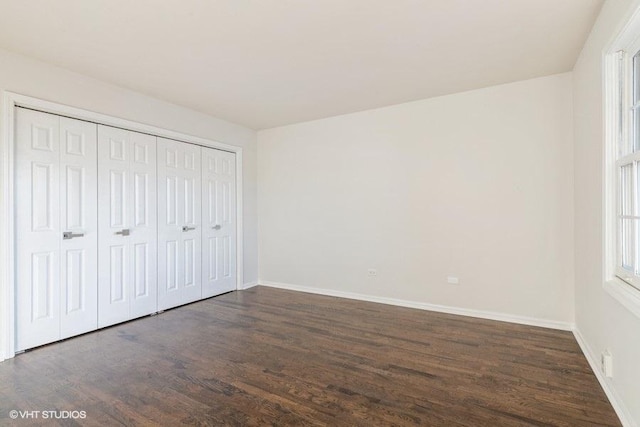 unfurnished bedroom with dark hardwood / wood-style flooring and a closet