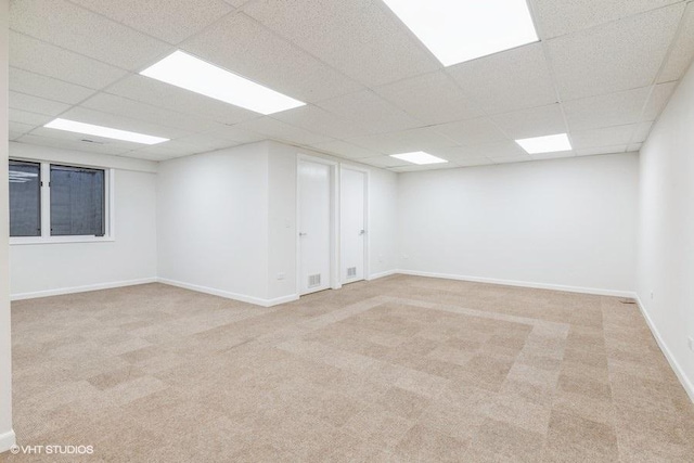 empty room featuring light colored carpet and a drop ceiling