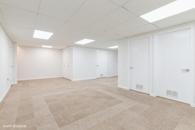 basement featuring light carpet and a drop ceiling