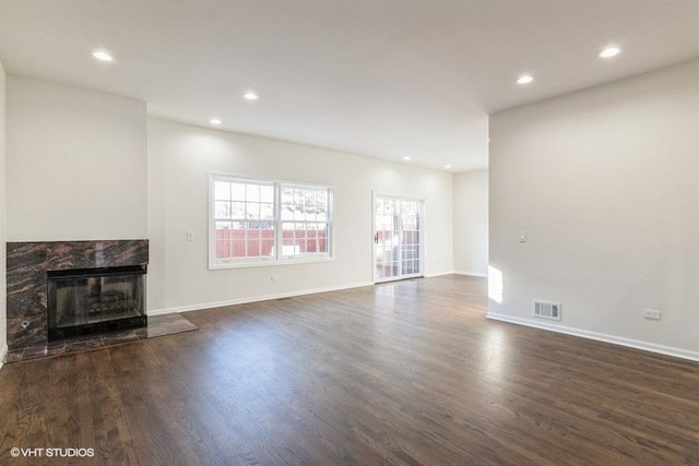 unfurnished living room featuring a high end fireplace and dark hardwood / wood-style flooring