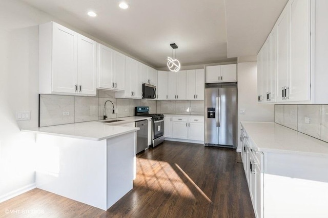 kitchen with stainless steel appliances, white cabinetry, decorative light fixtures, and dark hardwood / wood-style floors