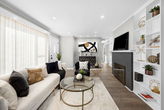 living room with built in features, crown molding, a fireplace, and wood-type flooring